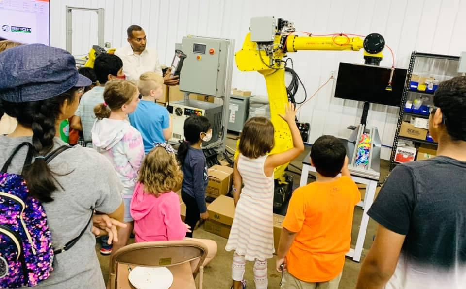 Carma Case hosting young students in STEM programs looking at machinery.