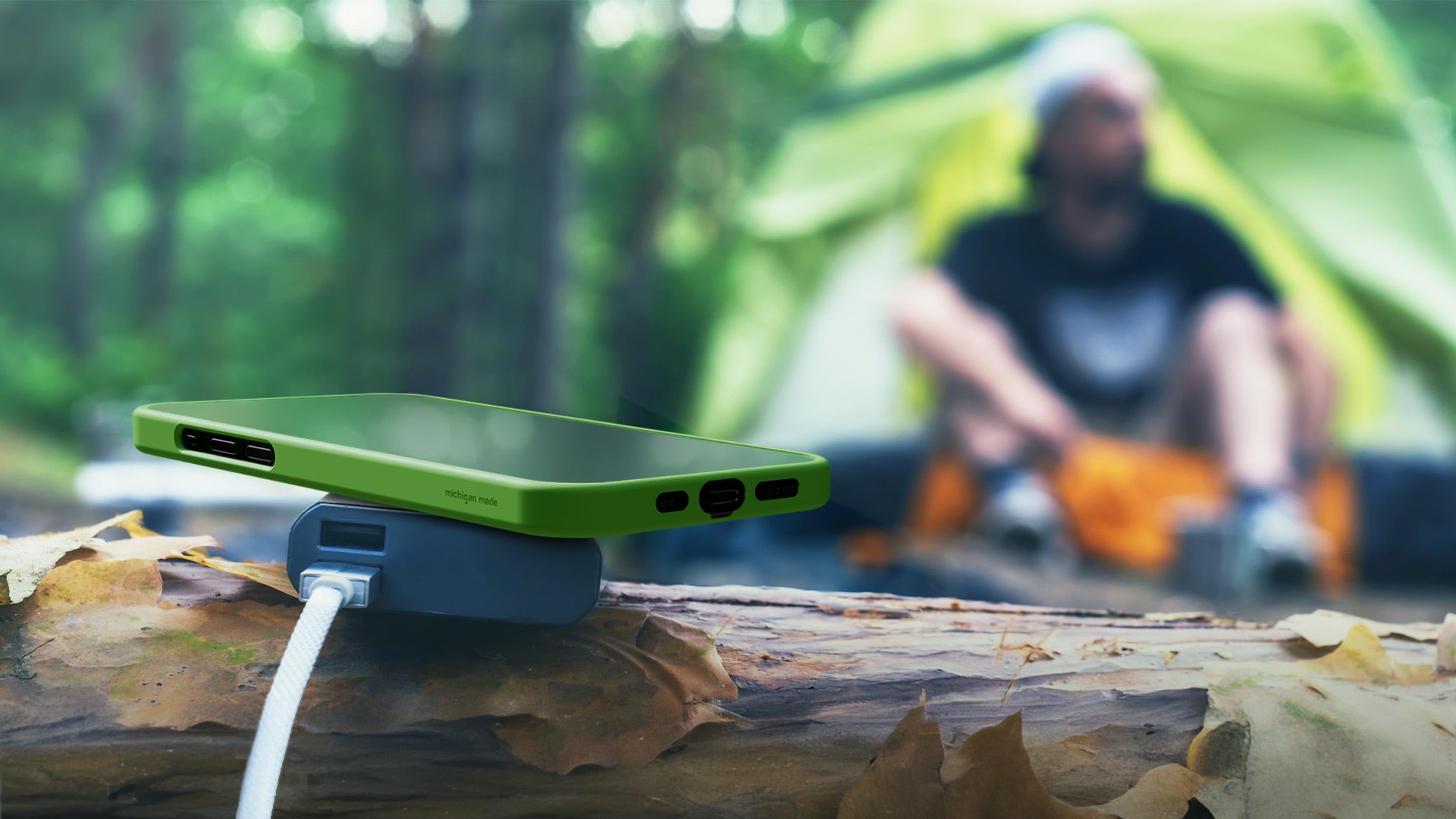 green case case with iphone charging outside at campground
